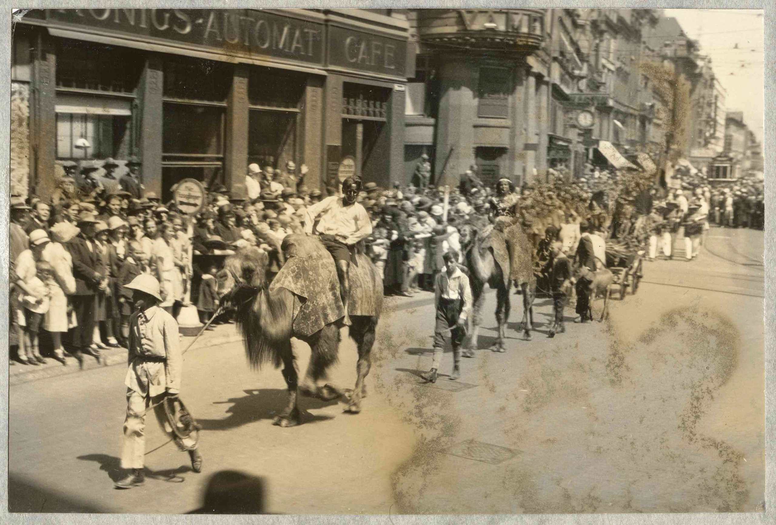 Schwarz angemalte Weiße werden während der Kolonialtagung 1928 in Stuttgart auf Kamelen durch die Straßen Stuttgart geführt